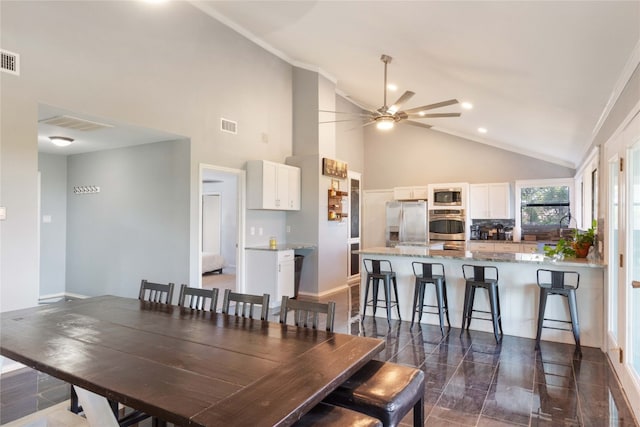 dining area with ceiling fan and high vaulted ceiling