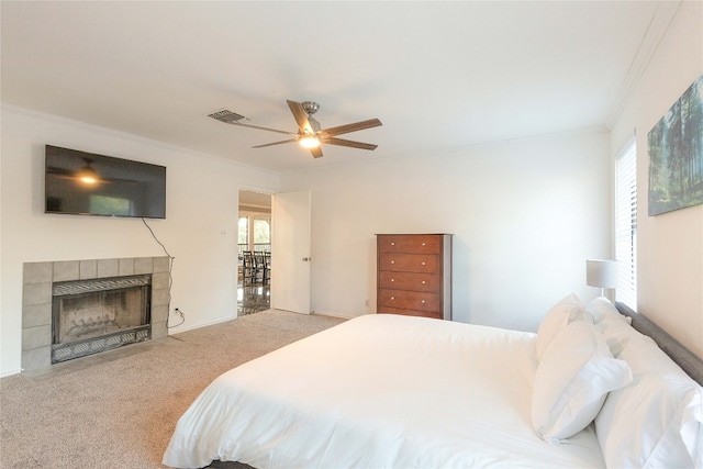 carpeted bedroom featuring multiple windows, ceiling fan, a tile fireplace, and ornamental molding