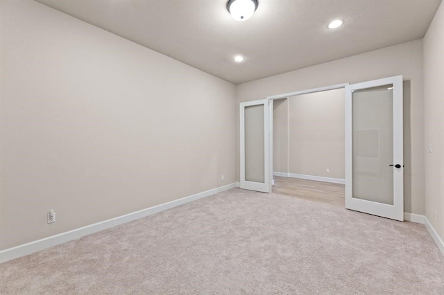 unfurnished bedroom with a closet, french doors, and light carpet