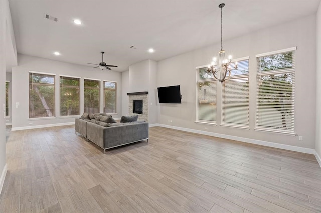 unfurnished living room with ceiling fan with notable chandelier and light wood-type flooring