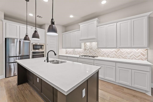 kitchen featuring white cabinetry, a center island with sink, and stainless steel appliances