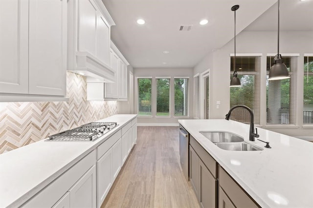 kitchen with white cabinets, sink, hanging light fixtures, light hardwood / wood-style floors, and stainless steel appliances