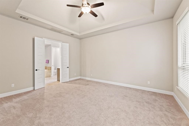 unfurnished bedroom featuring a tray ceiling, ceiling fan, and light colored carpet