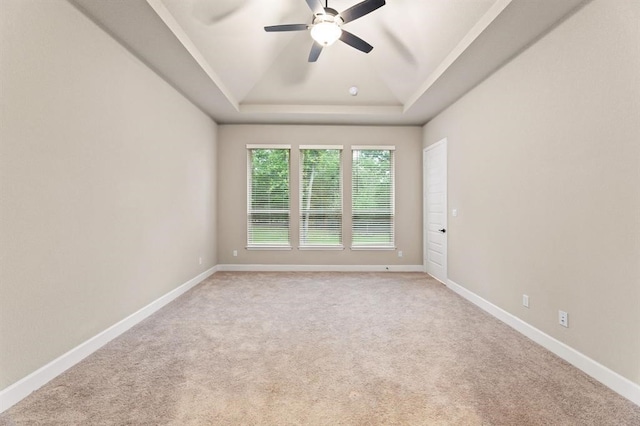 unfurnished room with a tray ceiling, light carpet, and ceiling fan