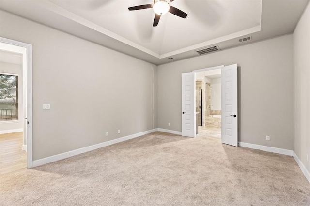 spare room with a tray ceiling, ceiling fan, and light colored carpet