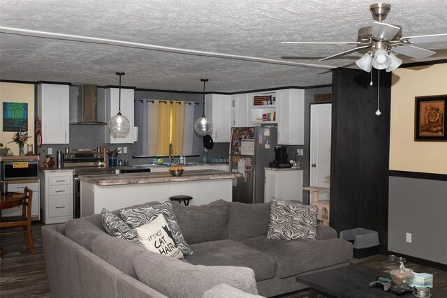 living room featuring a ceiling fan, dark wood finished floors, and a textured ceiling