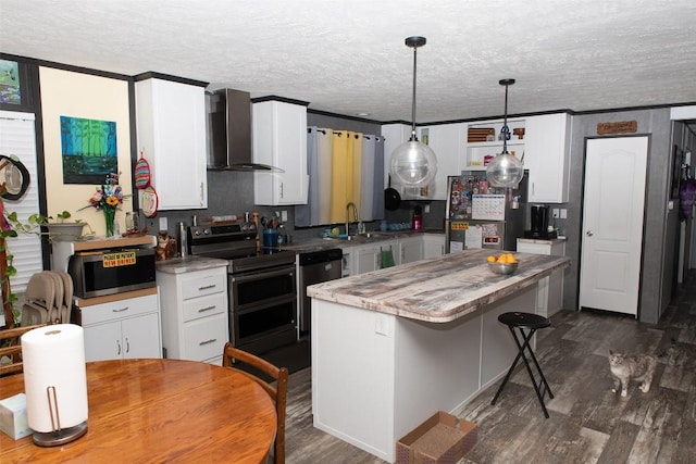 kitchen featuring wall chimney range hood, a kitchen island, a textured ceiling, appliances with stainless steel finishes, and dark wood finished floors