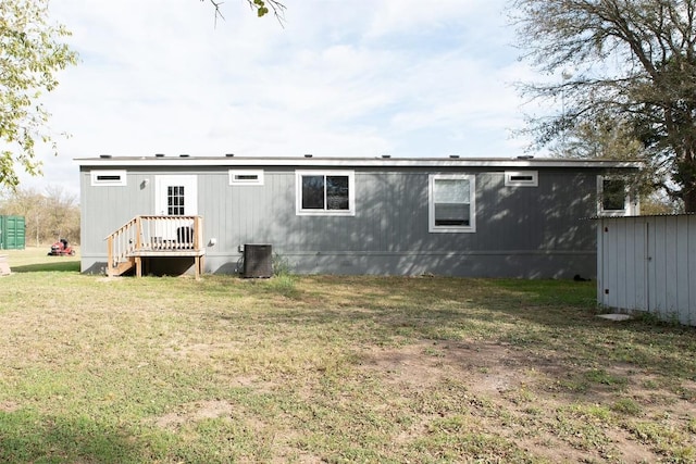 rear view of property featuring a yard, central AC, an outbuilding, and a storage shed