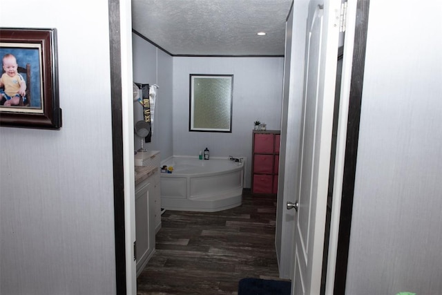full bath with a textured ceiling, a garden tub, and wood finished floors