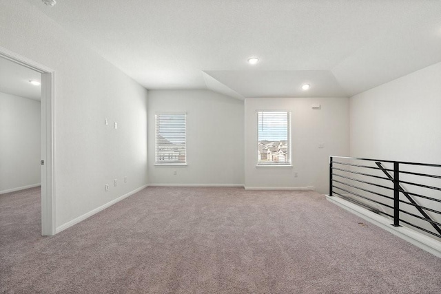 carpeted empty room featuring vaulted ceiling