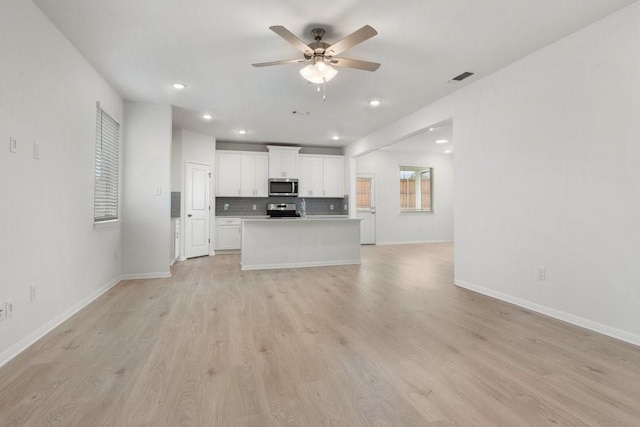 kitchen with ceiling fan, white cabinetry, stainless steel appliances, a kitchen island, and light wood-type flooring