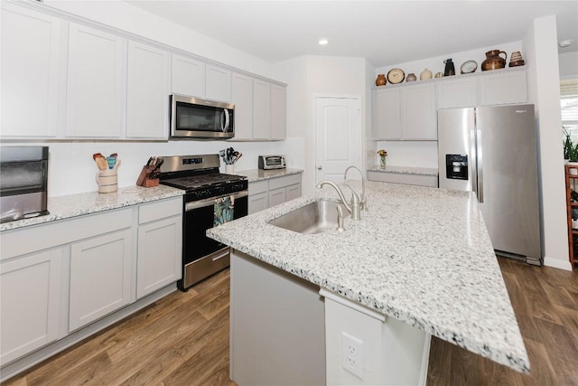 kitchen featuring hardwood / wood-style floors, appliances with stainless steel finishes, a kitchen island with sink, and sink