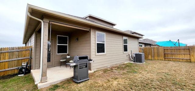 rear view of house featuring a patio, central AC unit, and a lawn