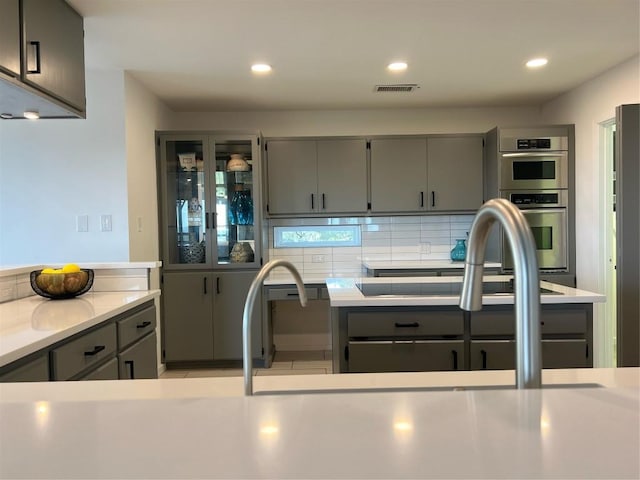 kitchen with gray cabinetry, oven, and backsplash