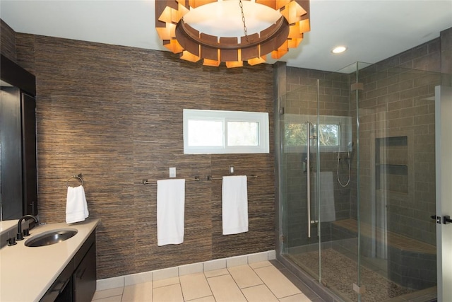 bathroom featuring tile patterned flooring, vanity, a shower with door, and tile walls