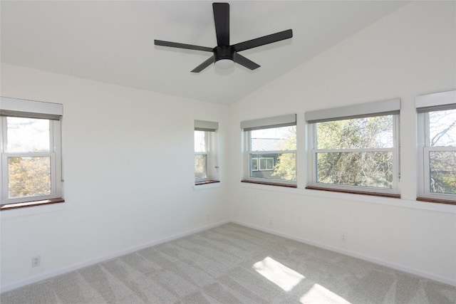 carpeted spare room featuring plenty of natural light, ceiling fan, and vaulted ceiling