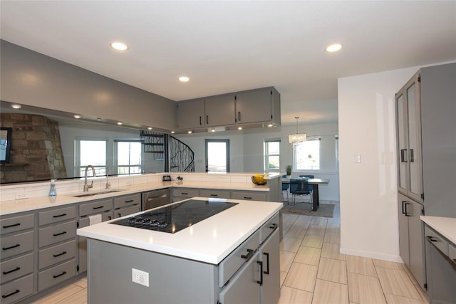 kitchen featuring black electric stovetop, a center island, gray cabinets, and sink