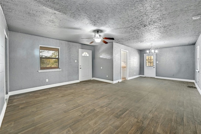 unfurnished living room featuring ceiling fan with notable chandelier, dark wood-type flooring, and a textured ceiling