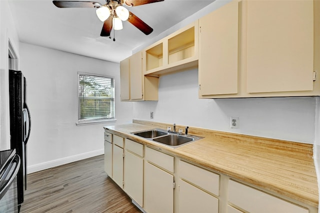 kitchen featuring sink, ceiling fan, stainless steel range, cream cabinetry, and wood-type flooring