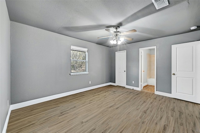 unfurnished bedroom featuring hardwood / wood-style floors, a textured ceiling, ensuite bath, and ceiling fan