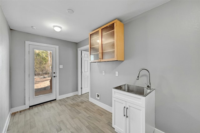 kitchen with white cabinets, light wood-type flooring, and sink