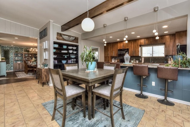 dining space with beamed ceiling, sink, and an inviting chandelier