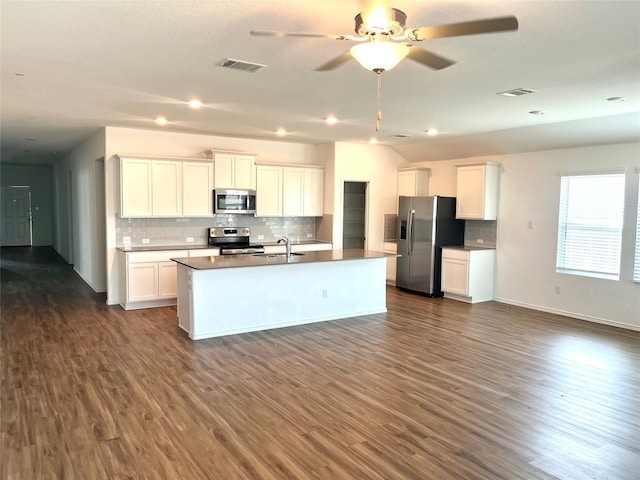 kitchen with appliances with stainless steel finishes, white cabinetry, dark wood-type flooring, and sink