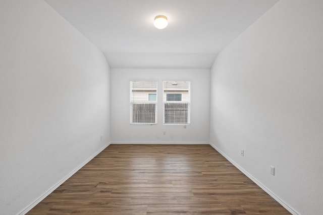 unfurnished room with dark hardwood / wood-style floors and vaulted ceiling