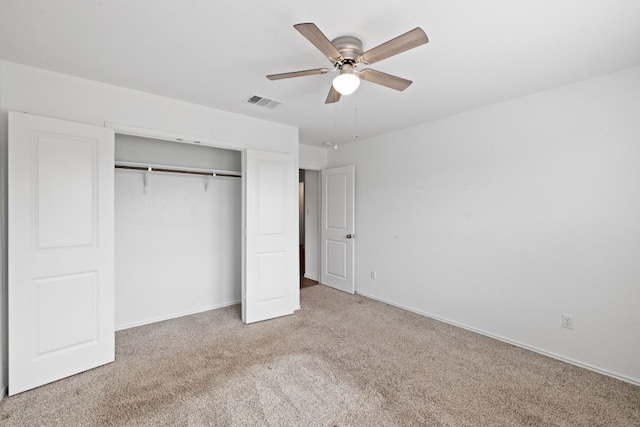 unfurnished bedroom featuring a closet, light colored carpet, and ceiling fan