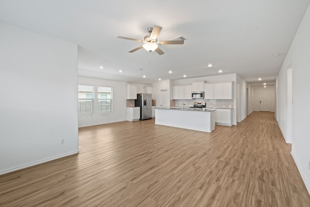 unfurnished living room featuring ceiling fan, sink, and light hardwood / wood-style flooring