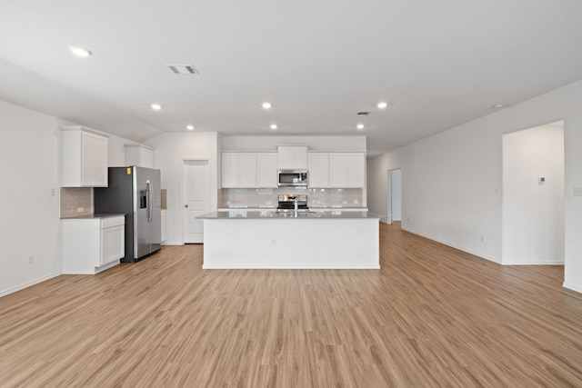 kitchen featuring stainless steel appliances, tasteful backsplash, a kitchen island with sink, white cabinets, and light wood-type flooring