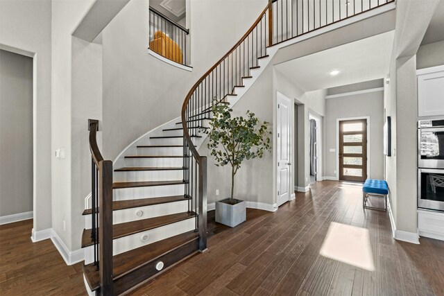 staircase featuring wood-type flooring and a high ceiling