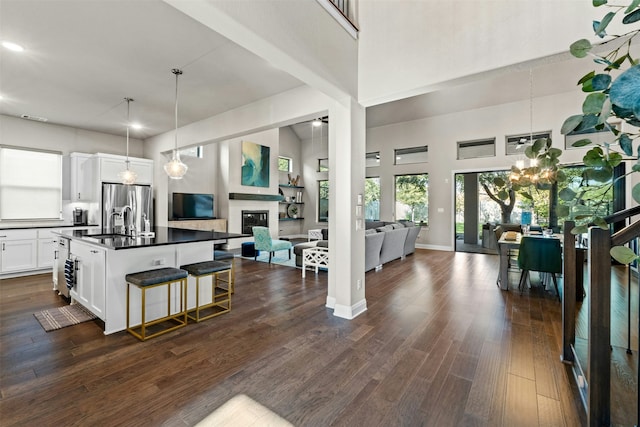 kitchen featuring sink, stainless steel fridge with ice dispenser, a kitchen breakfast bar, an island with sink, and white cabinets