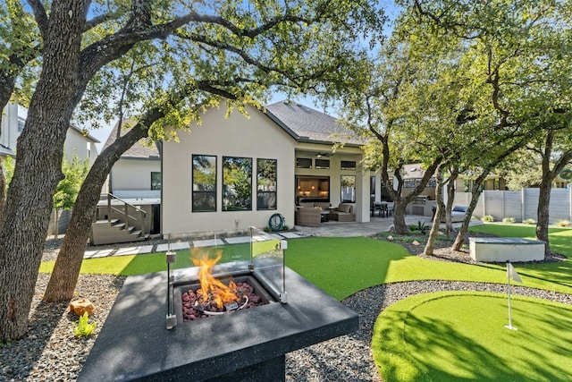 rear view of house with ceiling fan, a patio, and an outdoor living space with a fire pit