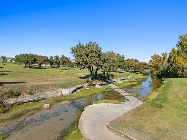 surrounding community with a water view and a yard