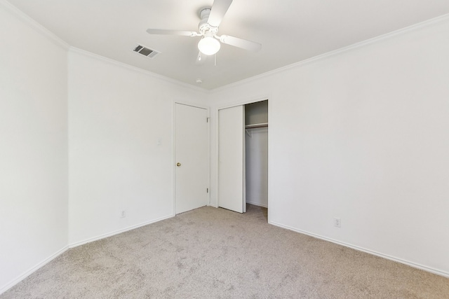 unfurnished bedroom featuring a closet, ceiling fan, crown molding, and light colored carpet