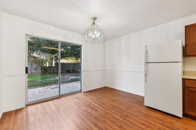 unfurnished dining area with light hardwood / wood-style floors and an inviting chandelier