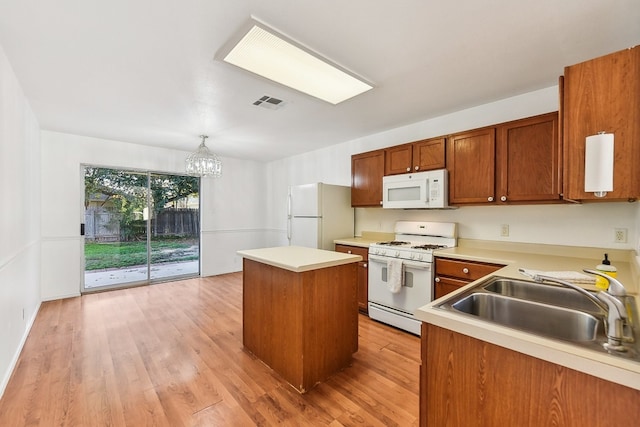 kitchen featuring an inviting chandelier, pendant lighting, light hardwood / wood-style floors, white appliances, and a kitchen island