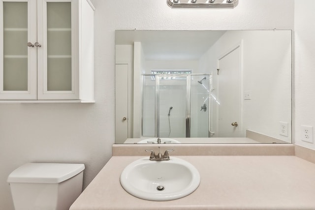 bathroom featuring vanity, toilet, and a shower with shower door