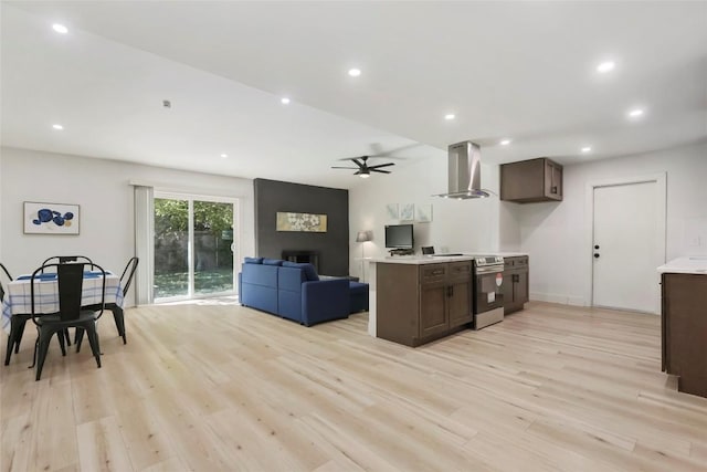 kitchen with ceiling fan, light wood-type flooring, wall chimney range hood, and electric stove