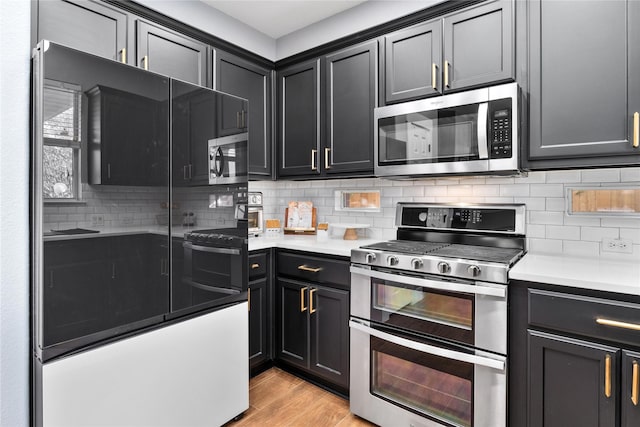 kitchen with backsplash, appliances with stainless steel finishes, and light wood-type flooring