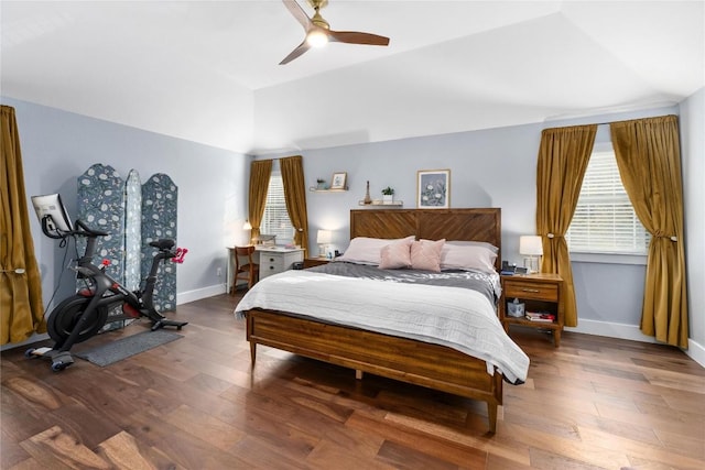 bedroom featuring ceiling fan, multiple windows, hardwood / wood-style floors, and lofted ceiling