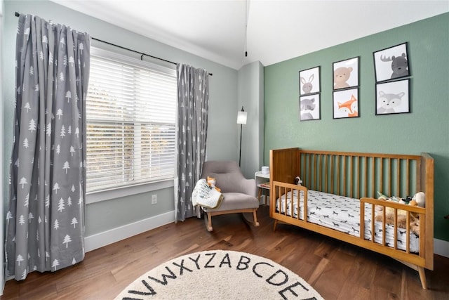 bedroom with a crib and hardwood / wood-style flooring