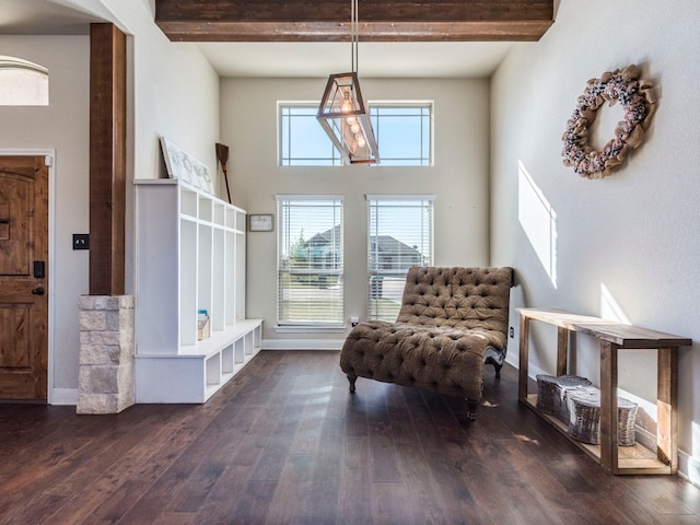 living area featuring beamed ceiling, dark hardwood / wood-style floors, and a towering ceiling