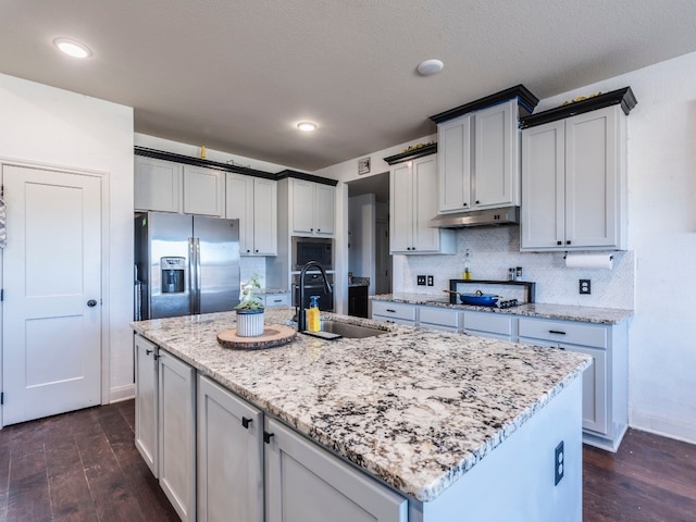 kitchen with dark wood-type flooring, an island with sink, stainless steel appliances, and sink