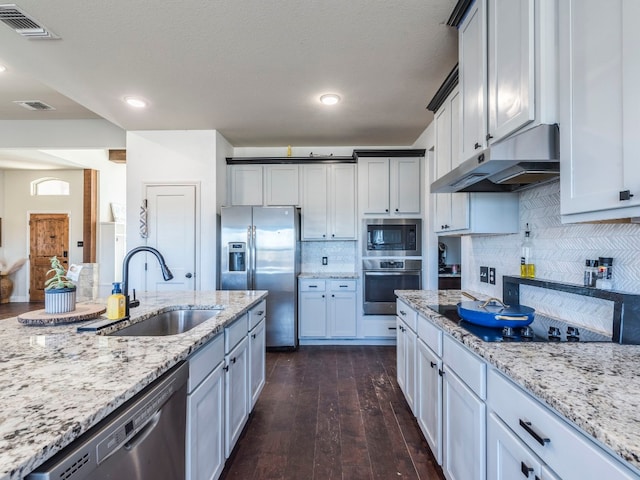 kitchen featuring light stone countertops, sink, tasteful backsplash, dark hardwood / wood-style flooring, and appliances with stainless steel finishes