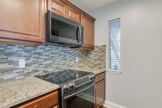 kitchen with appliances with stainless steel finishes, tasteful backsplash, and light stone counters