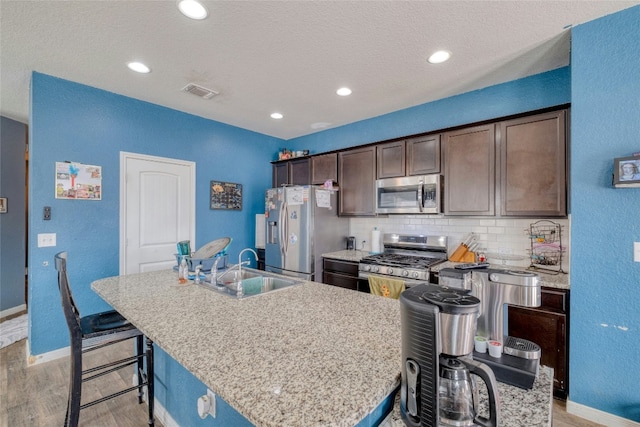 kitchen featuring appliances with stainless steel finishes, a center island with sink, dark brown cabinets, and sink