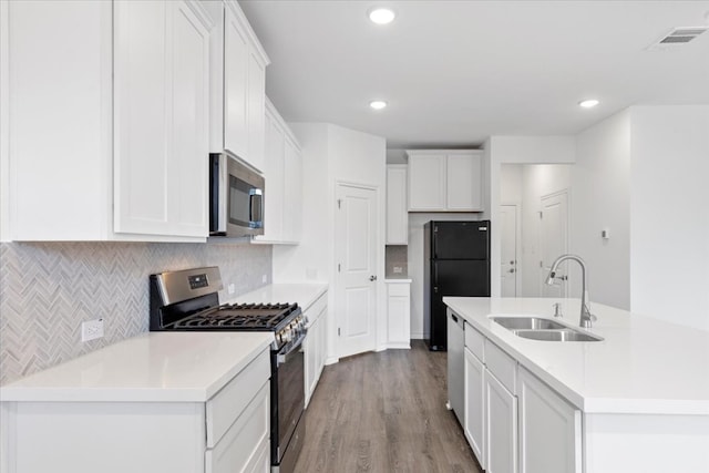 kitchen with sink, stainless steel appliances, light hardwood / wood-style flooring, a center island with sink, and white cabinets