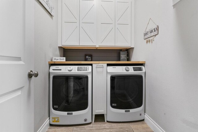 laundry area featuring cabinets, separate washer and dryer, and light hardwood / wood-style flooring